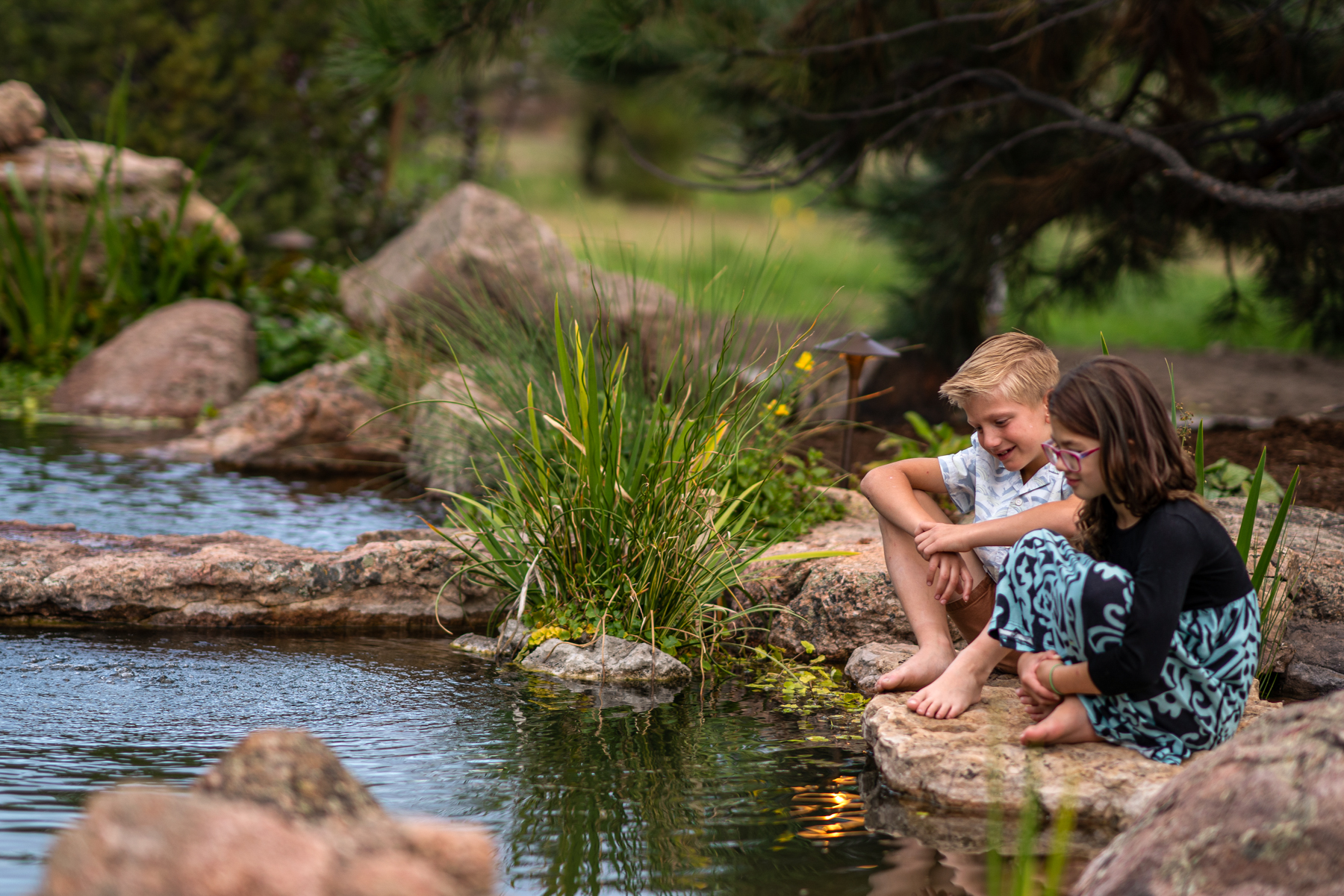 kids sitting at the edge of a backyard water feature